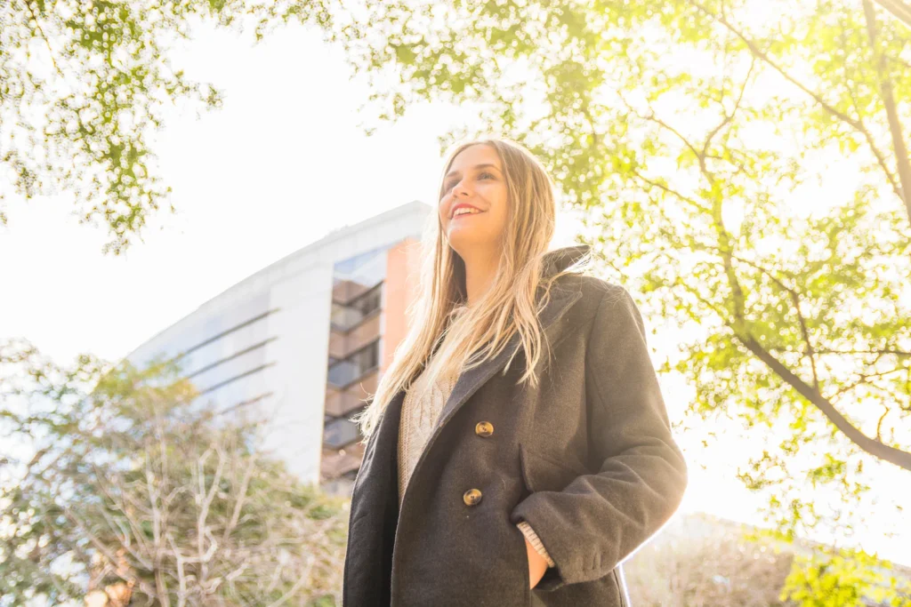 Curso online de Programación Neurolingüística (PNL) Fundación Human talent: mujer sonriendo con árboles y edificios al fondo