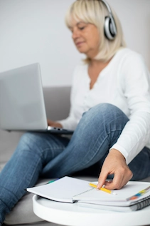 Mujer sentada estrudiando con un portatil y auriculares